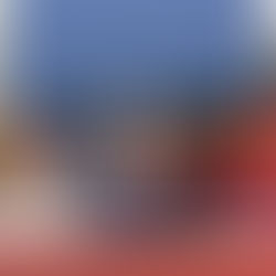 A diverse group in colorful outfits poses on a riverside platform at dusk. A central figure in a crown forms a heart shape with hands.