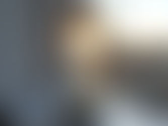 Sunlit hourglass on a windowsill, glowing in warm light with a blurred house and trees outside.