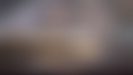 Open Bible lying on a glossy surface reflects faintly. Soft-focus stone wall in the background. Calm and serene atmosphere.