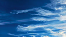 Wispy white clouds stretch across a bright blue sky, creating a serene and peaceful atmosphere. No text is visible.
