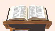 Open book with tiny text on a wooden lectern against a pale pink background, suggesting study or reading.