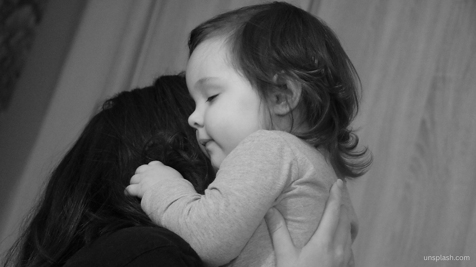 Child hugging an adult, eyes closed, in a warm embrace. Monochrome setting with soft lighting, creating a calming, tender mood.