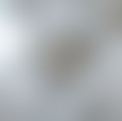 Stone sculpture of a sorrowful man with beard and crown of thorns, leaning against a cross. The background is a cloudy sky.