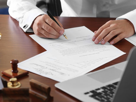 Person signing legal documents at a desk with notary tools