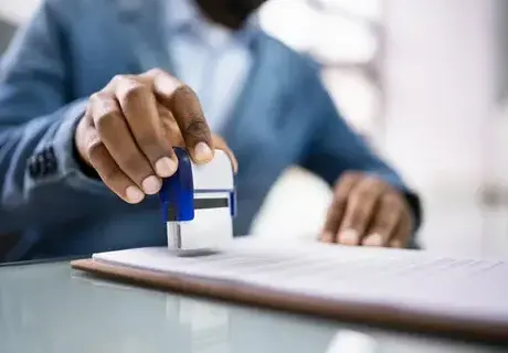 Person stamping and notarizing a document on a desk.