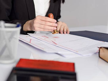 Person stamping documents for notarization on a desk.