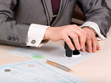 Notary stamping documents at a desk.