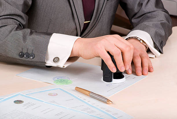 Notary stamping documents at a desk.