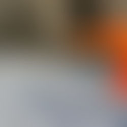 A worker skillfully applies decorative flakes to a freshly coated floor in an industrial setting, enhancing its appearance with a speckled texture.