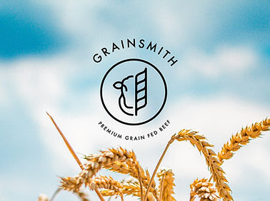 A logo for Grainsmith, using a stylized cow and wheat, with the text "Premium Grain Fed Beef" against a blue sky background