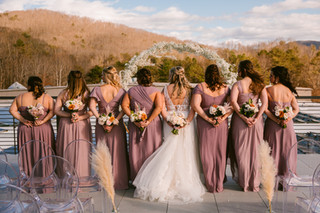 Bride and bridesmaids standing in a row holding their bouquets behind their backs