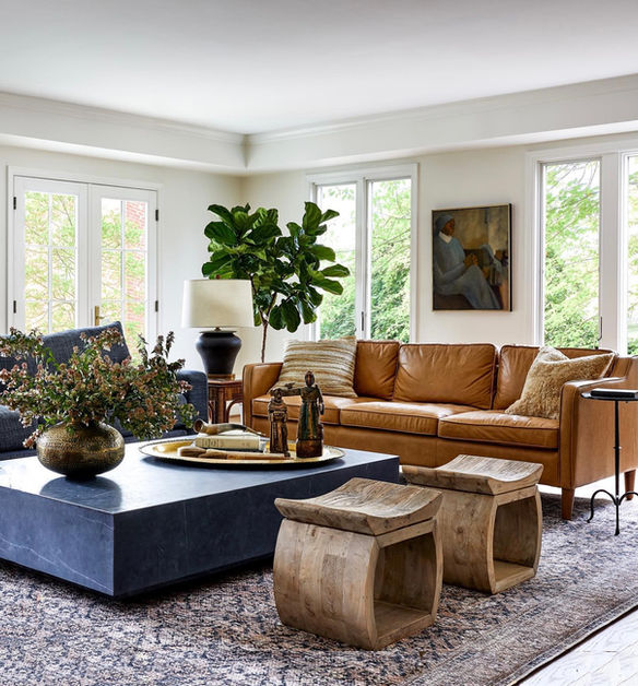 Modern living room with leather sofa, large coffee table, and wooden stools