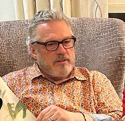 Man in glasses reads book in armchair