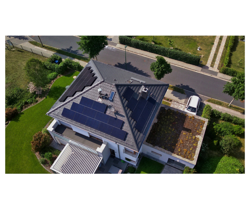 Luftaufnahme eines Privathauses mit Solarpanelen auf dem Dach (knapp 9,5 kWp, bestehend aus 28 Modulen à 340 Wp), entworfen und umgesetzt von Algatec, sowie einem Gründachanbau. Das Grundstück ist von gepflegten Gärten umgeben und liegt an einer Straße mit weiteren Häusern.
