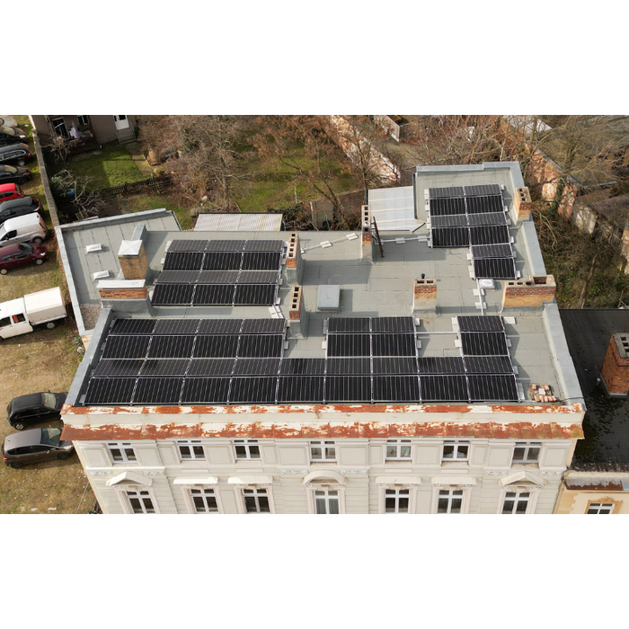 Luftaufnahme Dach eines weißen Gebäudes mit Gewerbe-Solaranlage (21,5 kWp) und Solarmodulen.
