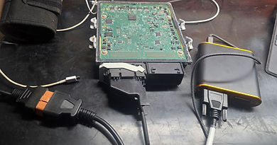 sid212 Electronic control unit on a black table, connected with various cables to a auto tuner device. Technical setup.