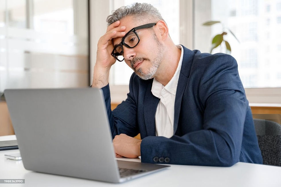 Overwhelmed male coach looking confused at his laptop, stressed by complex tech and Kajabi setup
