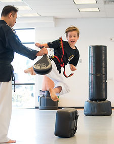 Martial arts training: student practices a flying side kick with expert guidance, focus, and energy at King Tiger Martial Art