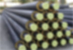 Large group of insulated pipes stacked outdoors for an engineering project.