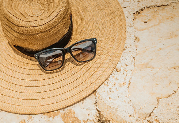 a sun hat and some sunglasses resting on top of the hat