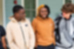 Three teenagers standing and laughing together.