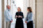 Three people having a standing conversation.