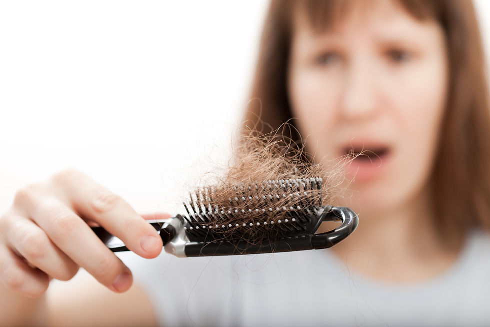 Woman holding a hairbrush full of hair, looking shocked. Blurry background emphasizes her surprise. Close-up on brush and hair.