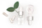 Dropper bottle with clear liquid, green leaves, and capsules on white background. The mood is fresh and clean.