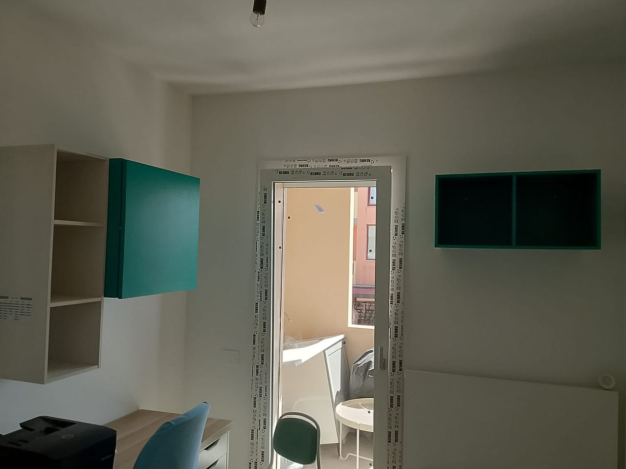 Zona giorno con mobili sospesi bianchi e pensili color petrolio.