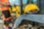 Operaio edile con casco giallo vicino a un escavatore