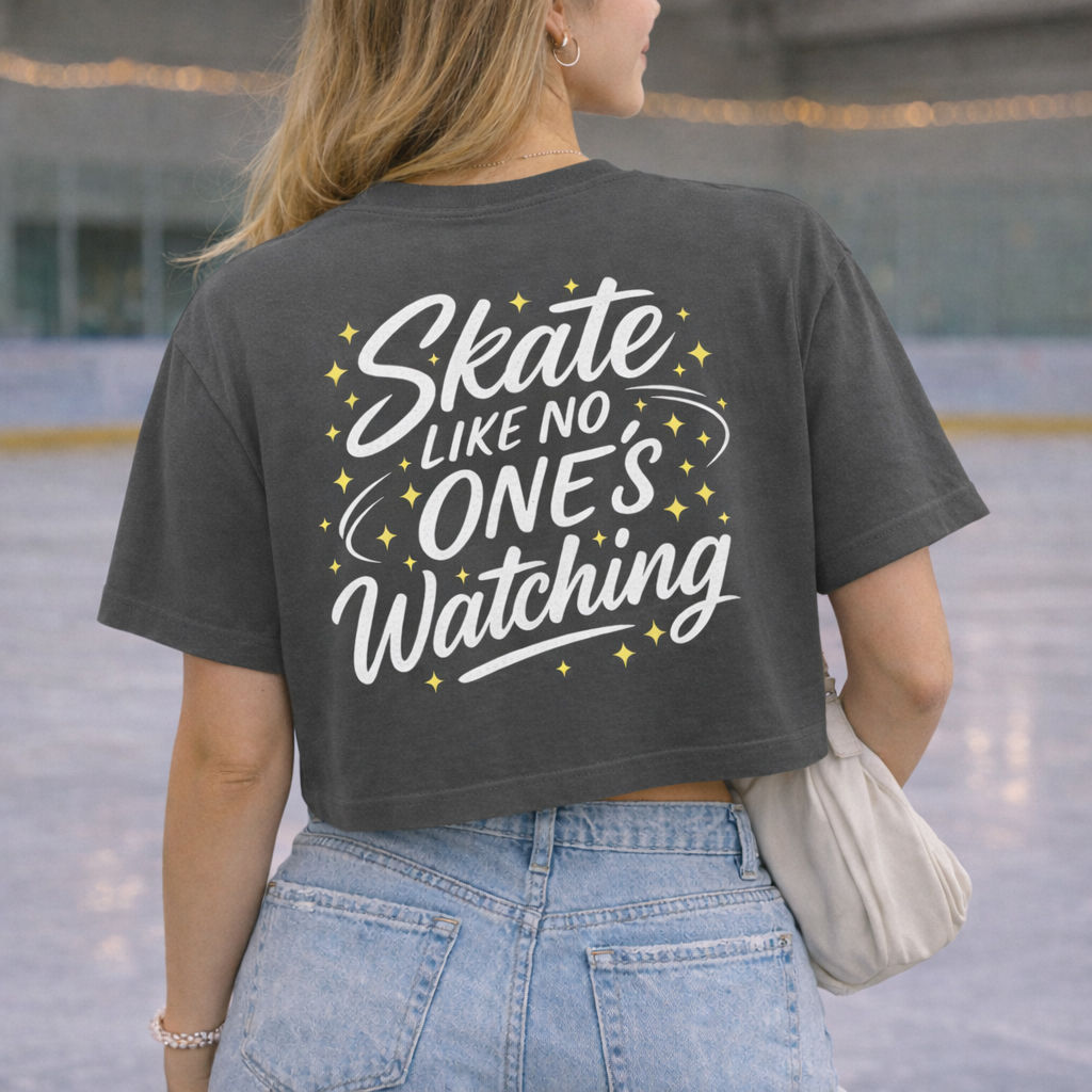 Back view of woman wearing charcoal Skate Like No One’s Watching cropped figure skating T-shirt at an ice rink