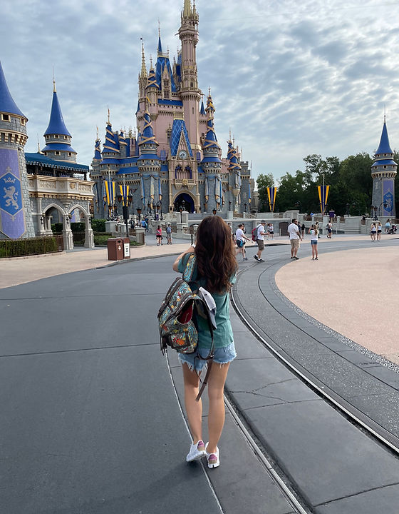 mom walking towards Cinderella Castle at Walt Disney World in Magic Kingdom Park carrying Gucci Disney backpack
