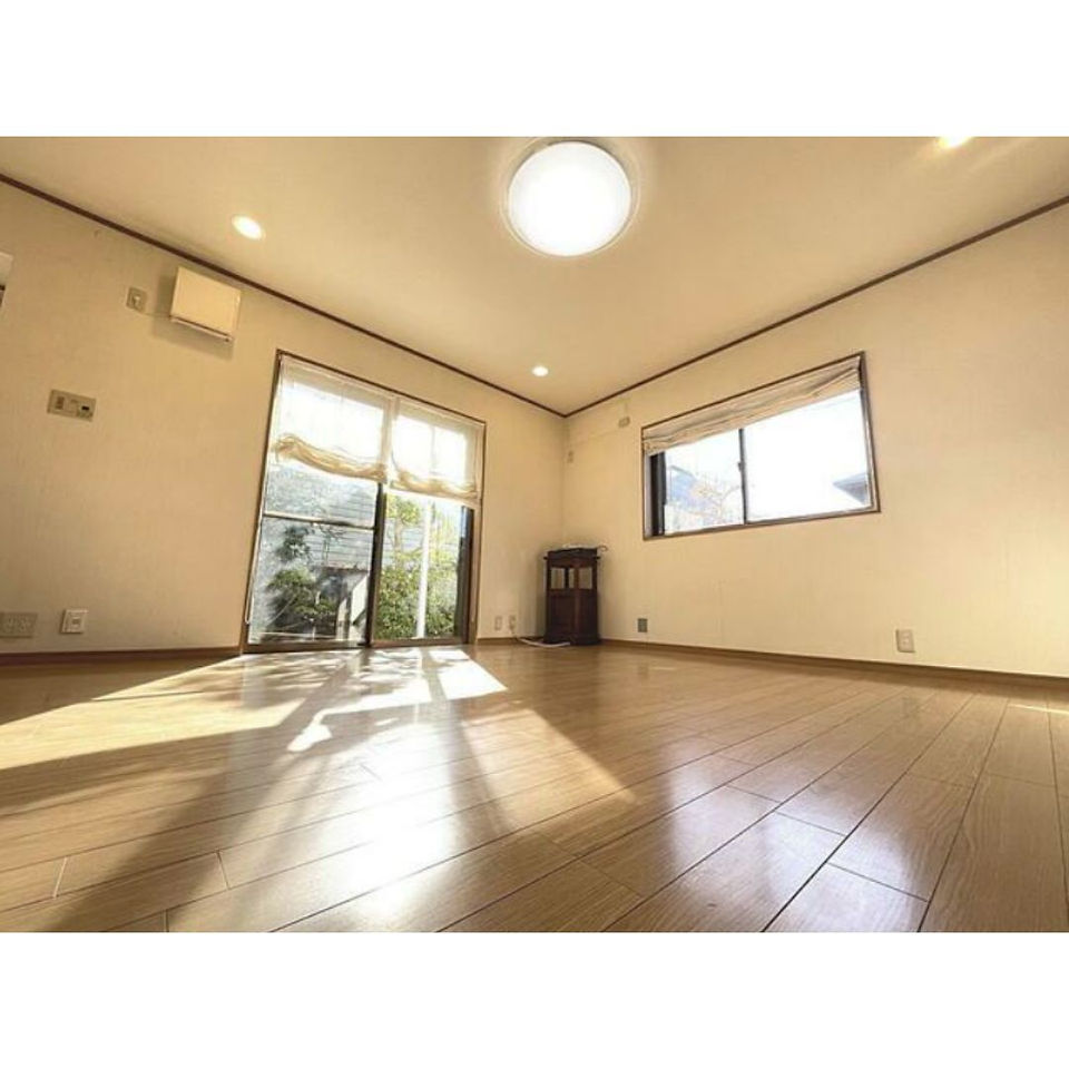 A spacious empty living room in Kawachinagano City, Osaka, featuring wooden floors and large windows allowing natural light.