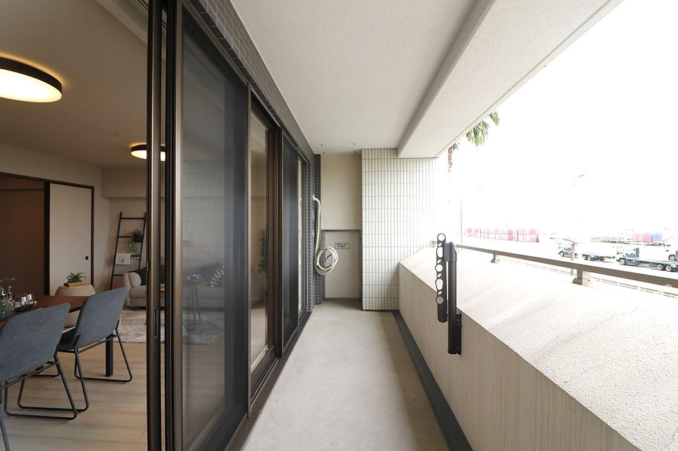 A spacious balcony with sliding glass doors offering a view of the surrounding area. A hose is attached to the wall.