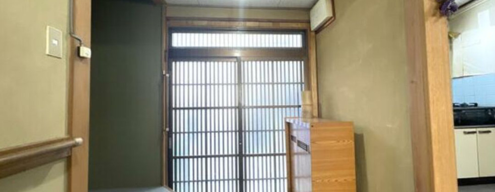 A room in a Kyoto 3DK house featuring a door, a window, and an entryway with a shoe closet for storage.