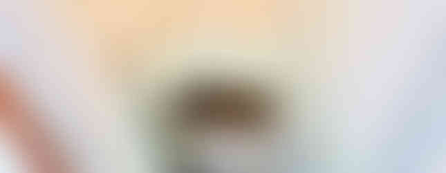 The image shows a small, dated bathroom with a stainless steel bathtub. The walls are tiled in a light blue and the floor is tiled in a light green. There is a small window on the wall and a door leading to another room. The bathroom appears to be in need of some renovation.