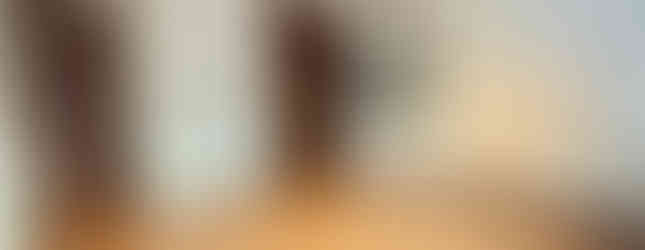 This photo shows a carpeted bedroom with white walls and a wooden closet. There is a door leading to a hallway with stairs visible in the background.