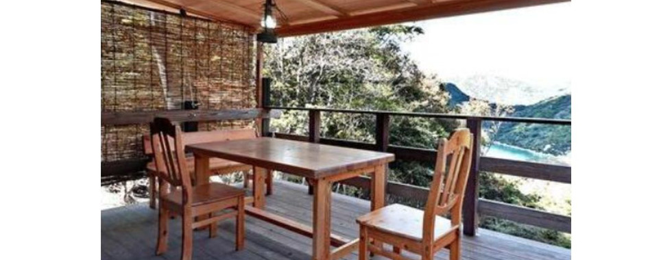 A wooden table and chairs on a back porch deck in Bizen City, Okayama Prefecture, with a stunning ocean view.
