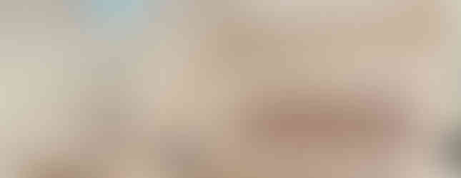 The image shows a small bathroom with pink tiles covering the walls and floor. There is a bathtub with a showerhead and a mirror above the sink. The bathroom appears to be well-lit and functional.