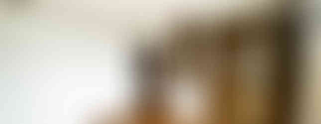 This image shows the interior of a bedroom. The room features a wooden floor, white walls, and a large closet with mirrored doors. There is also a door leading to another room.