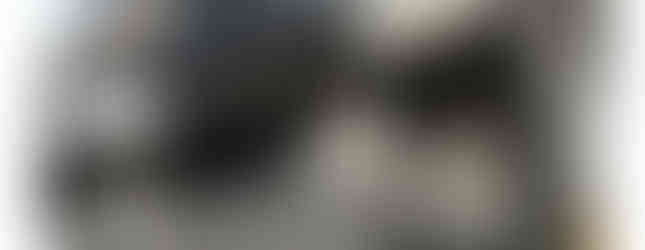 The image shows a two-story house with a garage. The house has a modern exterior with a gray color scheme. There is a balcony on the second floor and a carport on the first floor. The house looks well-maintained and has a clean appearance.