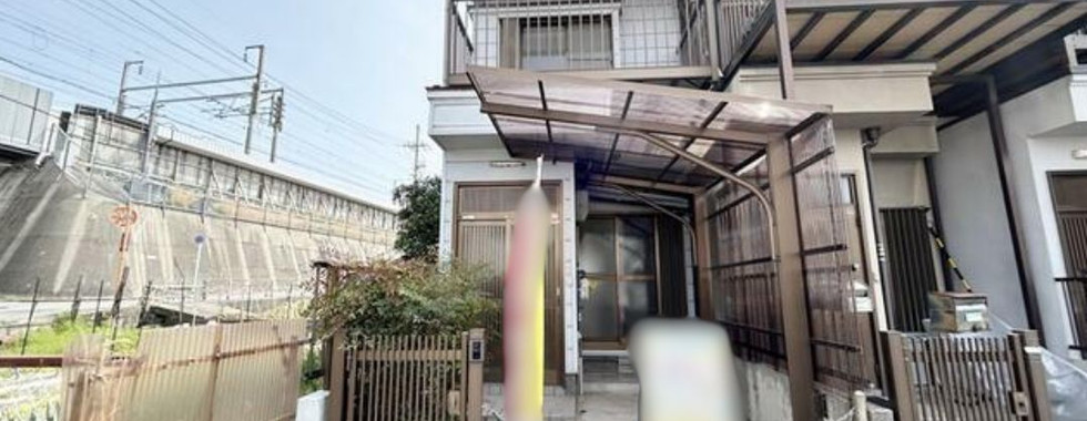 Two-story house with a metal roof and a small yard.