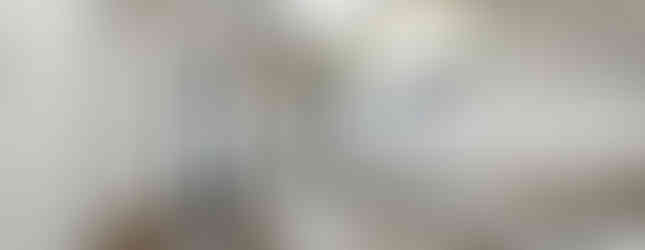 The photo shows a modern kitchen with white cabinets and a stainless steel countertop. The kitchen has a gas stove, a sink, and a range hood. There is a window above the sink that lets in natural light. The kitchen also has a door leading to another room, and a small window overlooking the outside. The overall impression is one of a clean, functional, and bright space.