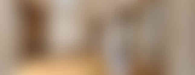 The photo shows a spacious room with a wooden floor. There are sliding doors on both sides of the room, leading to other areas of the house. There is also a closet in the corner of the room. The room is brightly lit with natural light coming in from windows.