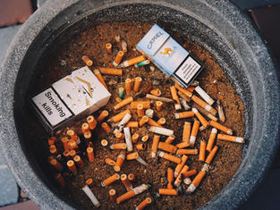 Ashtray filled with cigarette butts and two cigarette packs; one reads "Smoking Kills." The scene evokes a sense of caution.