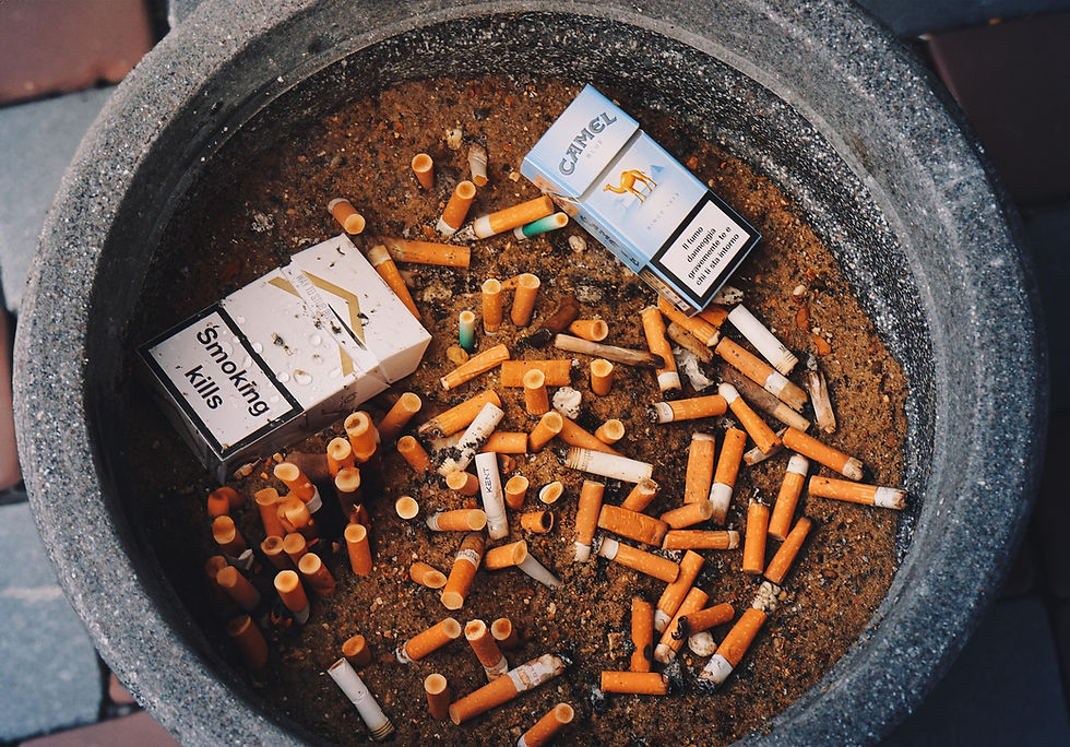 Ashtray filled with cigarette butts and two cigarette packs; one reads "Smoking Kills." The scene evokes a sense of caution.