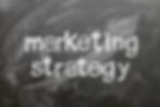 White "marketing strategy" on chalkboard with upward arrow for planning.