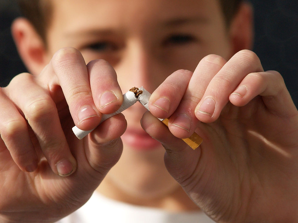 A person breaks a cigarette in half with both hands, background slightly blurred, conveying a message of quitting smoking.