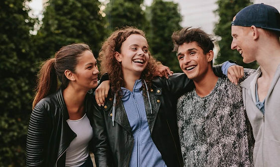four teens outside smiling and looking at each other