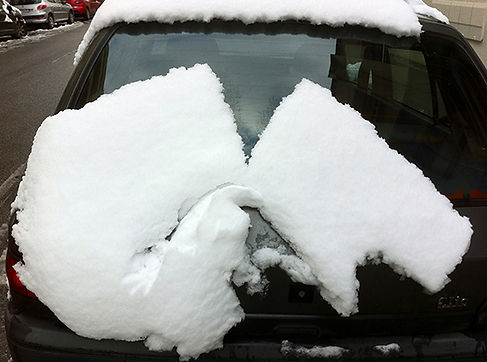 A l'arrière d'une voiture, en glissant, un bloc de neige s'est fendu en deux.
